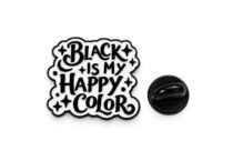 Black and white enamel pin reading Black Is My Happy Color with black butterfly clutch